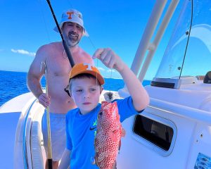 a man wearing a blue jacket standing on a boat posing for the camera