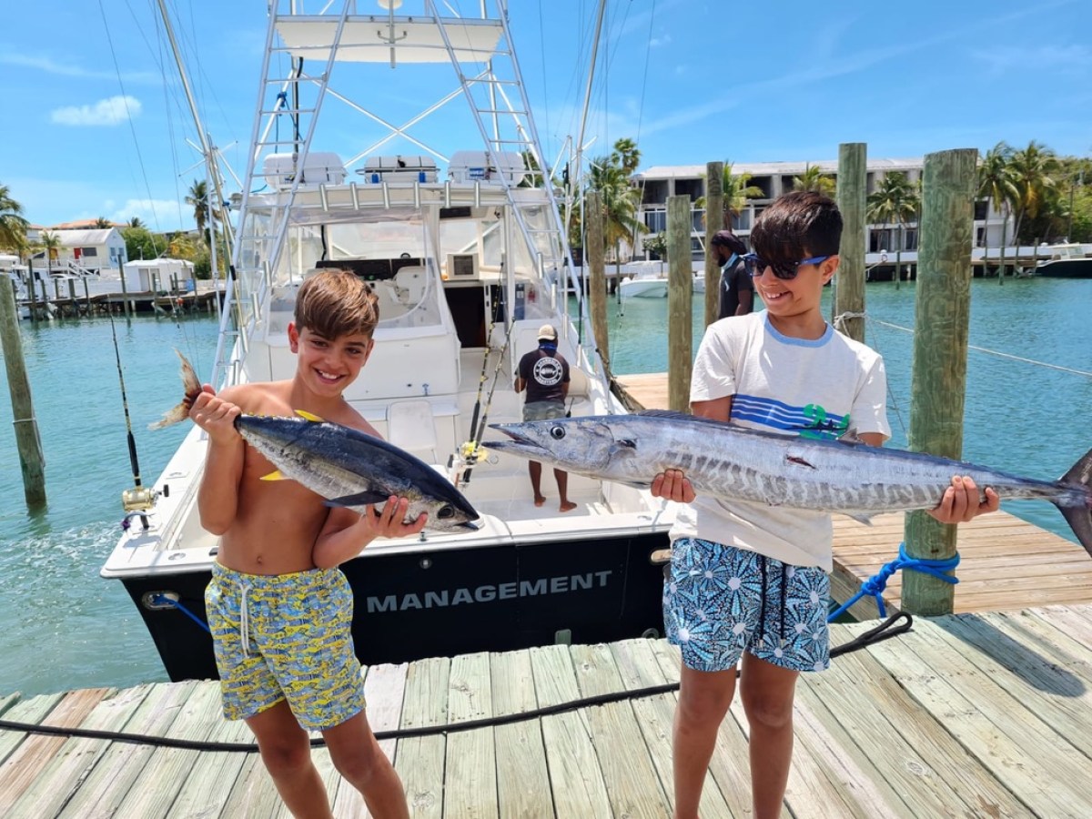 a man holding a fish on a boat in the water
