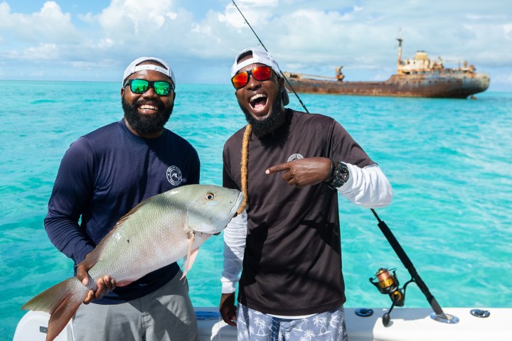 a man holding a fish on a boat in the water