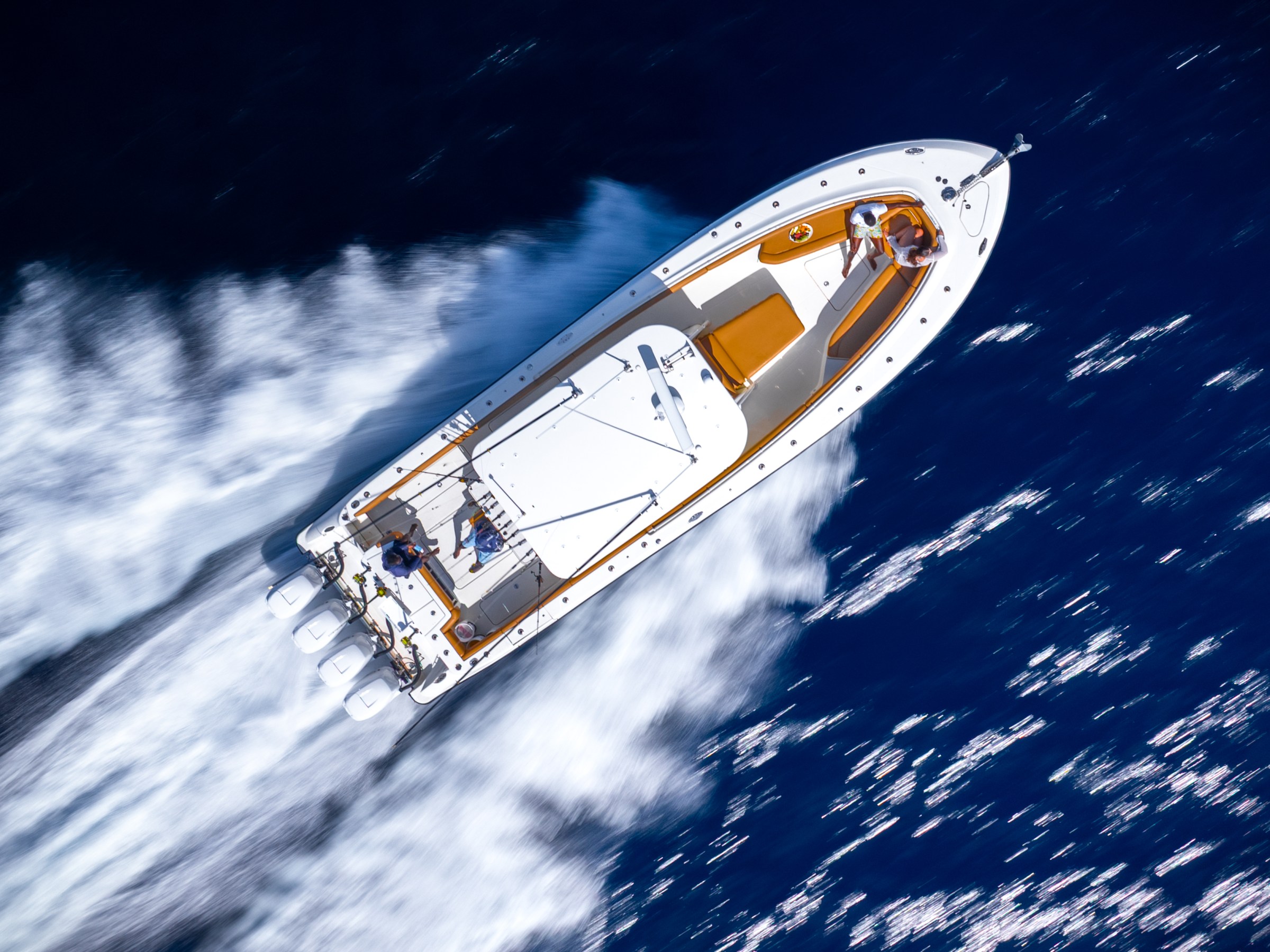 Aerial view of a speedboat with a wake trail in the ocean.